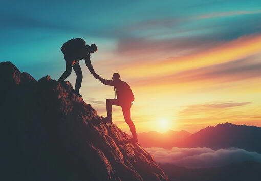 Silhouette of a guide helping another climb a mountain at sunrise, representing expert support and momentum